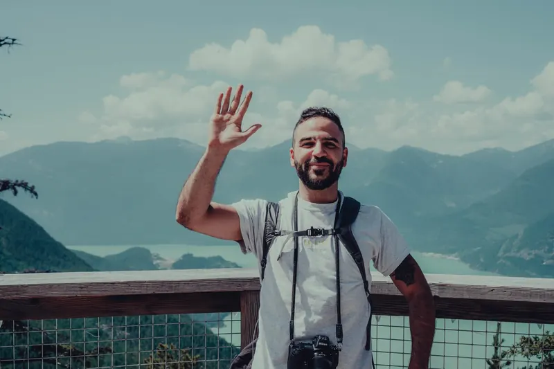 Jason Mikhow waving from a mountain lookout with his camera
