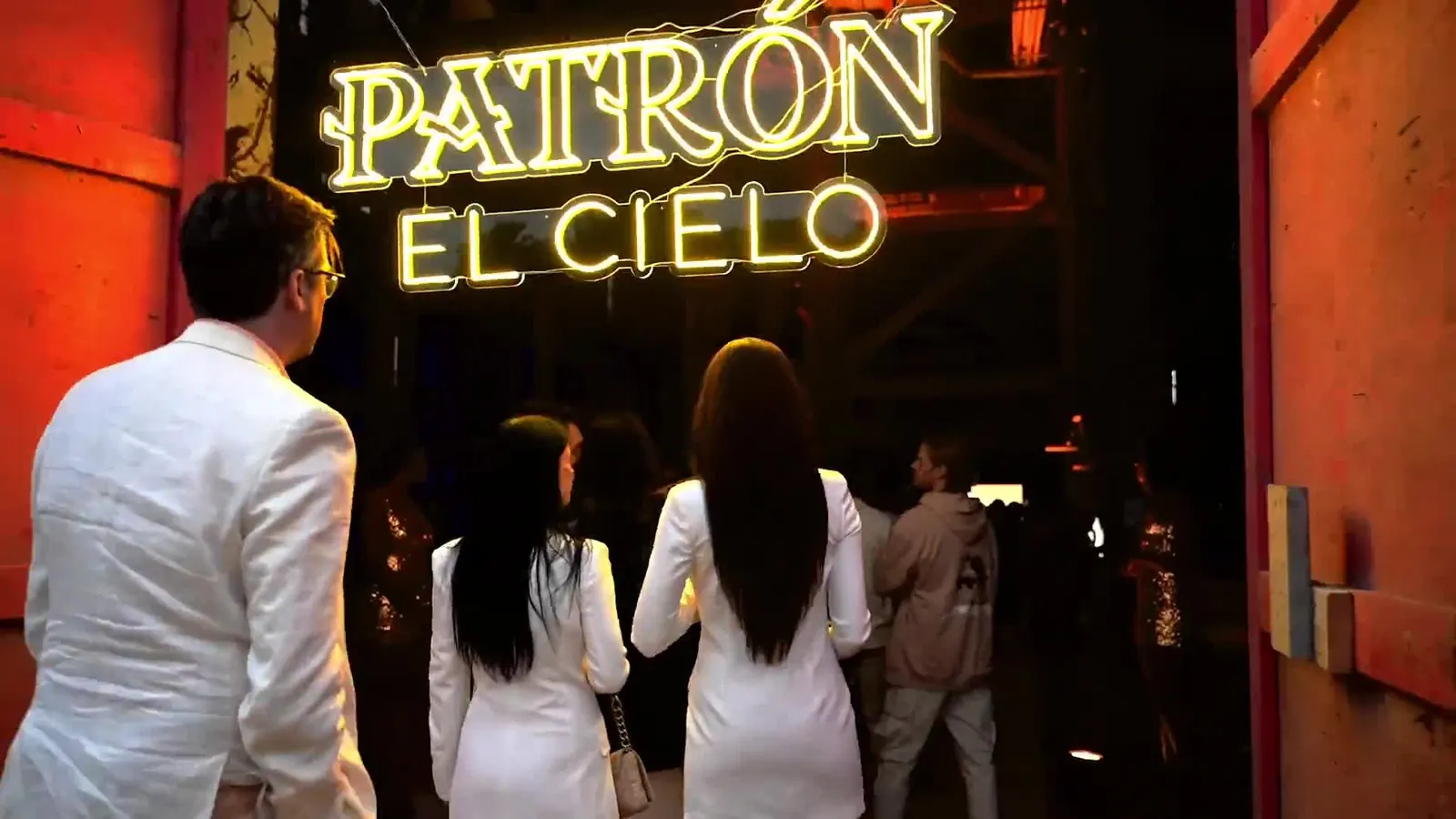 Guests in white walking toward a neon Patrón El Cielo sign at the event